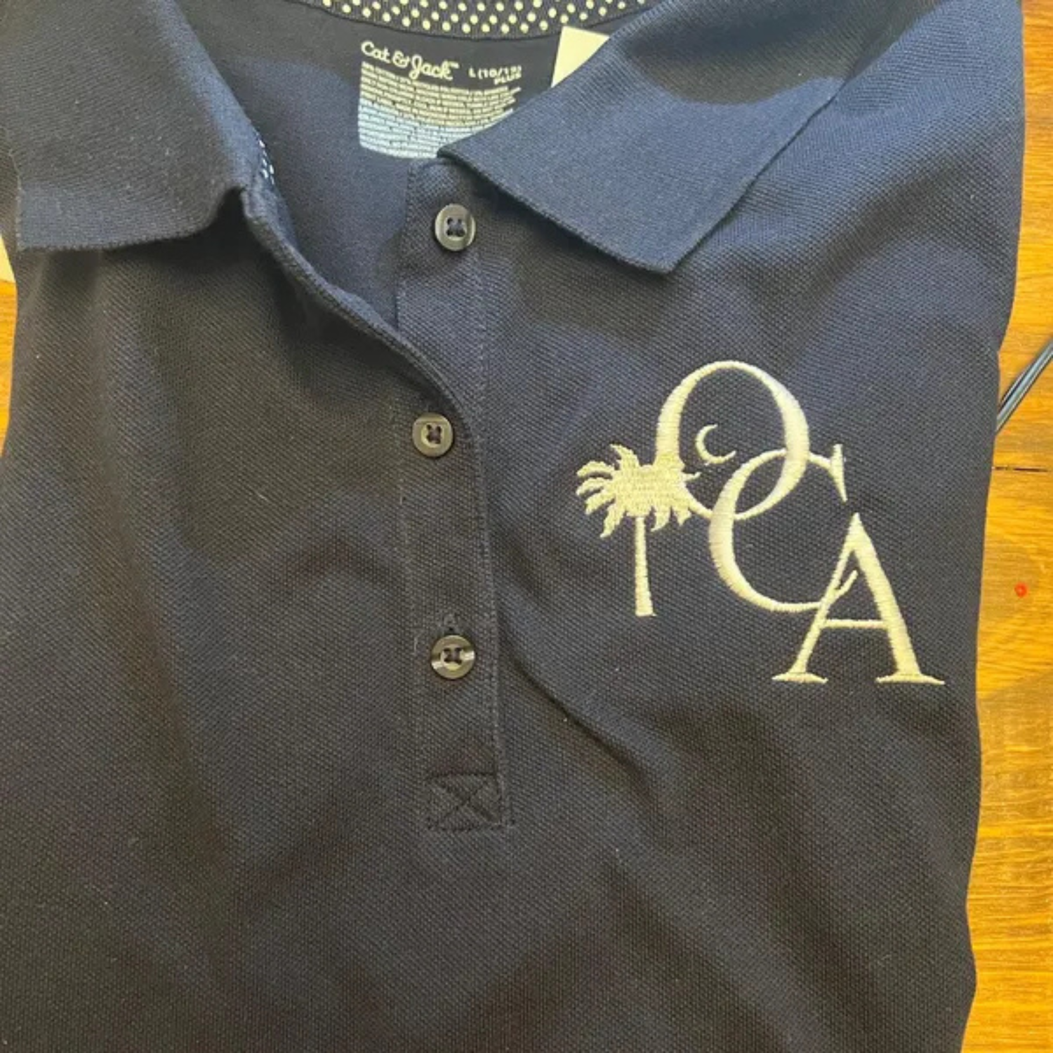 PCA monogram logo embroidery stitched on polo knit fabric